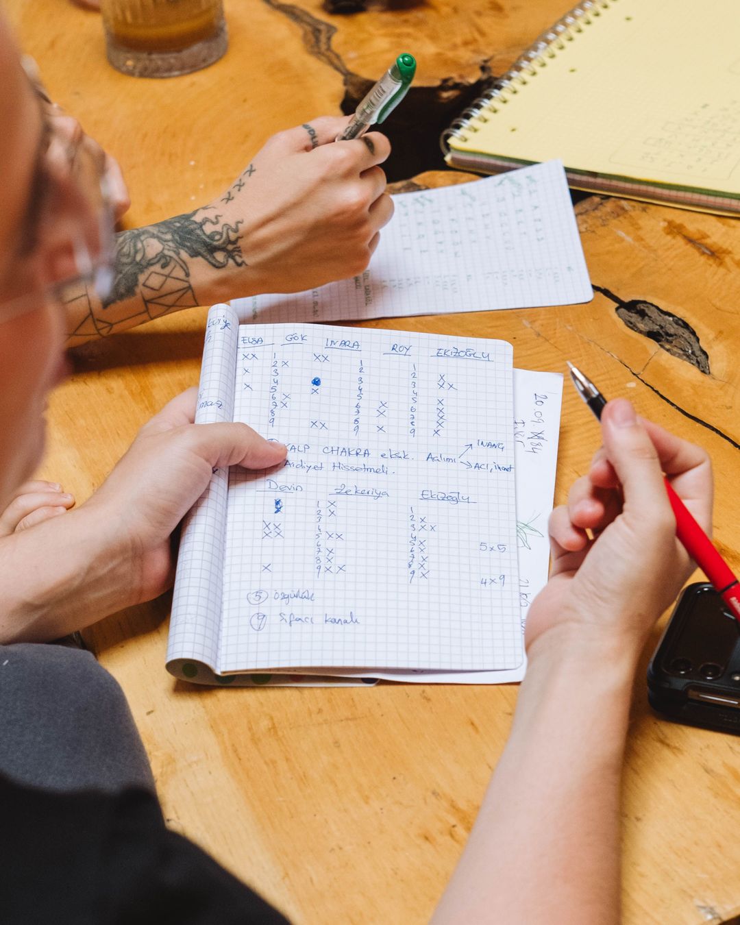 Two people working through plans and notes together at a wooden desk